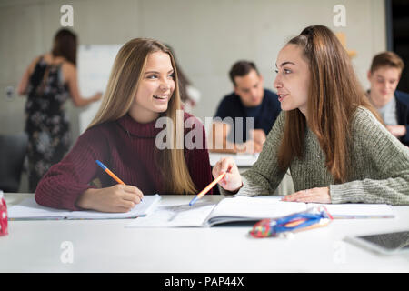 Smiling teenage girls talking in class Stock Photo