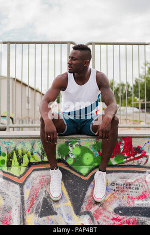 Young man in skatepark sitting on wall Stock Photo