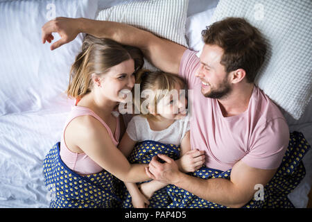 Happy family lying in bed, cuddling Stock Photo
