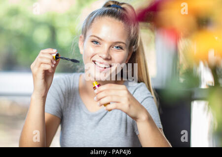 Portrait of smiling teenage girl applying makeup Stock Photo