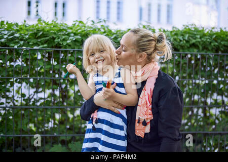 Portrait of laughing little girl with painted face in her mother's arm Stock Photo