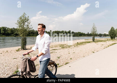Mature man with bike at Rhine riverbank Stock Photo