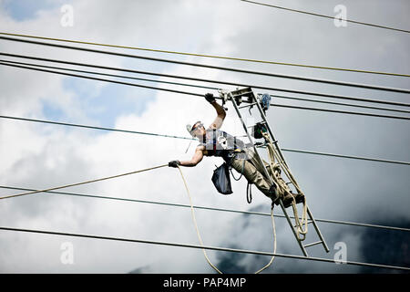 Fitter with ladder, pulling along high-voltage power line Stock Photo