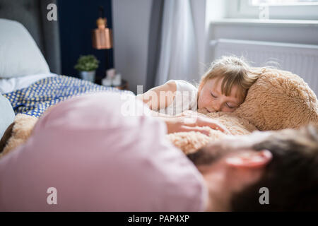 Father and daughter taking a nap, cuddling with teddy bear Stock Photo