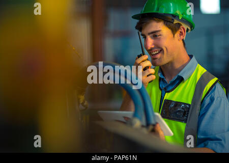 Engineer in industrial plant inspecting machines, using walkie-talkie Stock Photo