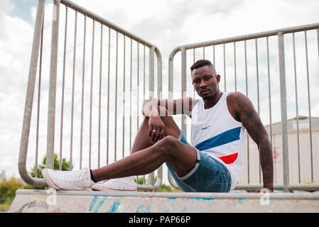 Young man in skatepark sitting on wall Stock Photo