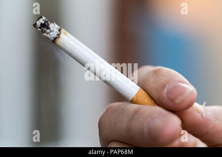 Man smoking a king size cigarette, with ash and smoke Stock Photo