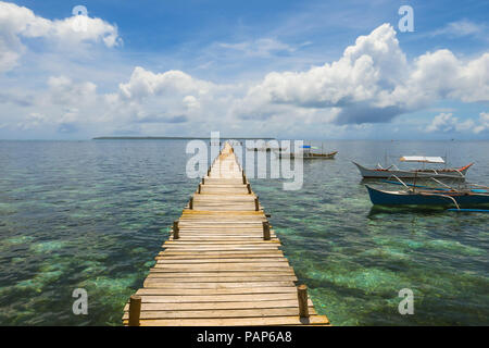 Wooden Plank Walkway Out At Sea, With Fluffy Clouds and Docked Fishing Boats - General Luna, Siargao island - Philippines Stock Photo