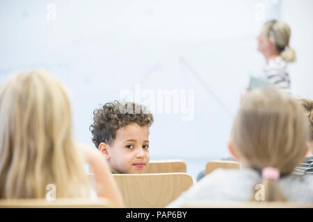 Portrait of schoolboy with classmates and teacher in class Stock Photo