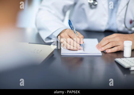 Doctor sitting at his desk taking notes Stock Photo