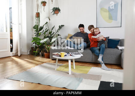 Family sitting on couch, using laptop Stock Photo