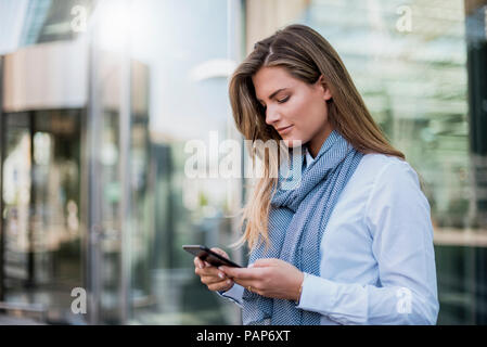 Young businesswoman looking at smartphone Stock Photo