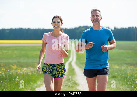 Couple running on field path Stock Photo