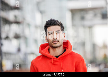 Portrait of fashionable young man wearing red hooded jacket Stock Photo