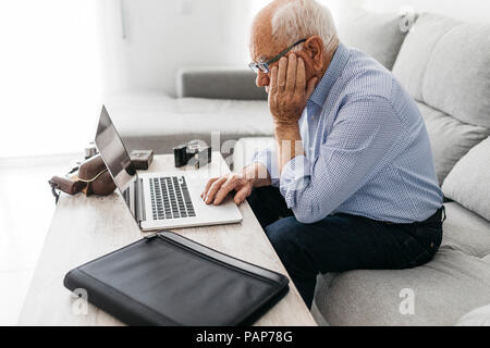 Senior man using laptop, old photo cameras Stock Photo