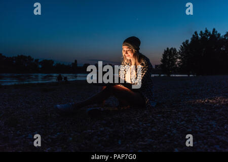 Young woman using smartphone on riverside in the evening Stock Photo