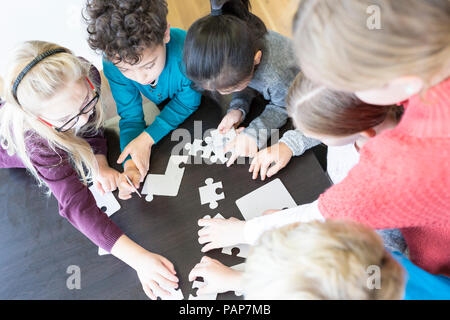 Pupils playing jigsaw puzzle in school together Stock Photo