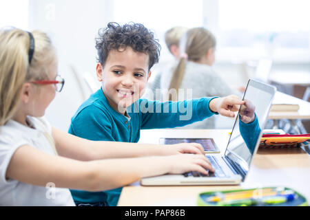 Schoolboy and schoolgirl using laptop together in class Stock Photo