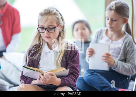 Schoolgirls reading books in school break room Stock Photo