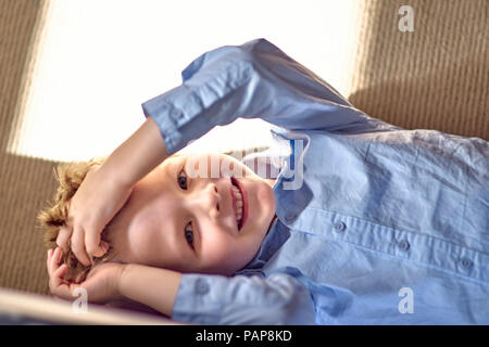 Portrait of happy boy lying on couch Stock Photo
