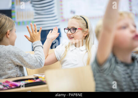 Happy schoolgirls high fiving in class Stock Photo