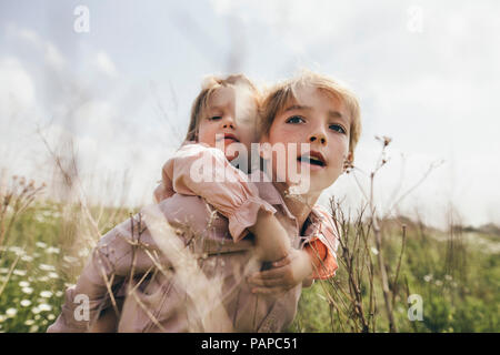 Portrait of boy giving his little sister a piggyback ride Stock Photo