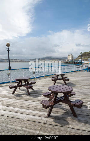 Picnic benches on the beautiful old pier at Llandudno, North Wales. View back towards the beach and hotels. Stock Photo