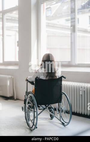 Young handicapped woman sitting in wheelchair, rear view