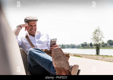Mature man using smartphone on bench Stock Photo