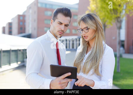 Serious managers discussing about financial datas on tablet, outdoors Stock Photo
