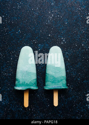 Superfood spirulina popsicles on dark background.Ideas and recipes for healthy breakfast,summer vegetarian snack,vegan dessert.Popsicle with spirulina powder, coconut milk.Top view.Copy space.Vertical Stock Photo