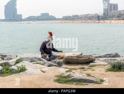 Drinks' seller sitting with his vendibles on the breakwater at the Barceloneta Beach by the Mediterranean sea. Stock Photo