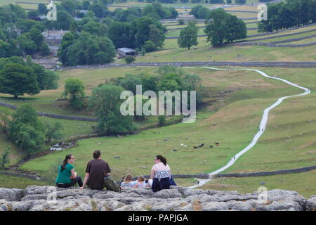 Visitors to Malham sit on top of one of the limestone pavements above Malham Cove Stock Photo