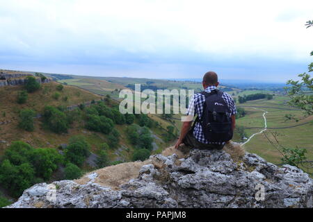 A tourist takes in the beautiful scenery of the Yorkshire Dales from the top of Malham Cove Stock Photo