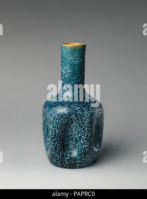Bottle vase. Culture: British. Designer: Christopher Dresser (British, Glasgow, Scotland 1834-1904 Mulhouse). Dimensions: Overall (confirmed): 9 1/2 × 4 7/8 × 4 7/8 in. (24.1 × 12.4 × 12.4 cm). Manufactory: Linthorpe Pottery Works (British, 1879-1889). Date: ca. 1882.  This vase illustrates a shape designed by Christopher Dresser during his partnership with the Linthorpe Pottery Works from 1879 to 1882. The dimpled bottle vase--model number 24--was produced in great numbers, but few have the beautiful and rare crackle glaze of the present vase. It is thought that Linthorpe glazes, particularly Stock Photo