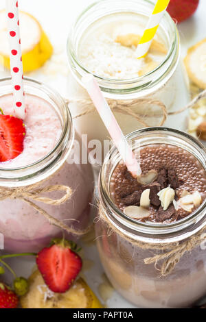 Set of milkshake in jars. Banana chocolate and strawberry milkshakes with nuts and coconut. Summer dessert. Close up. Stock Photo