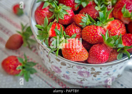 On the table on a napkin is dishes with red ripe strawberries. Stock Photo