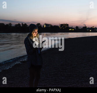 Young woman using smartphone on riverside in the evening Stock Photo