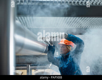 Female mechanic fixing pipework with gaspipe pliers Stock Photo