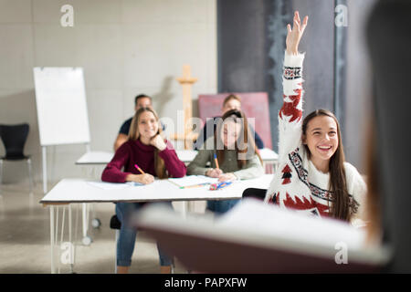 Smiling teenage girl raising hand in class Stock Photo