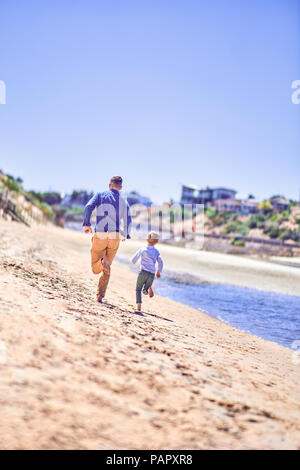 Australia, Adelaide, Onkaparinga River, father and son running on the beach Stock Photo