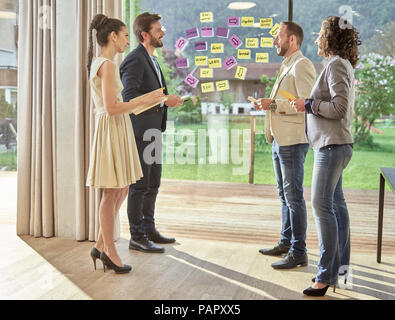 Colleagues discussing with sticky notes at the window Stock Photo