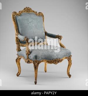 Armchair (fauteuil à la reine). Culture: Southwestern German. Dimensions: Overall: 43 1/4 × 29 1/2 × 23 1/2 in. (109.9 × 74.9 × 59.7 cm). Date: ca. 1750-60.  The flowing, curvilinear silhouette of this exuberantly carved armchair is close in inspiration to a design attributed to the French ornamentist and court goldsmith Juste-Aurèle Meissonier (1695-1750), who was named architect and designer to the king in 1726. Meissonier's chair is characterized by the same overall sweep of the back and cabochon-cartouches heading the legs, and a similar disposition of the armrests. As in the Museum's exam Stock Photo