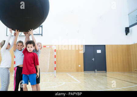 Pupils holding big ball in gym class Stock Photo
