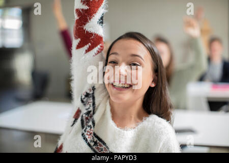 Smiling teenage girl raising hand in class Stock Photo