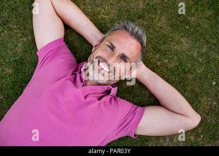 Portrait of smiling mature man lying in grass Stock Photo