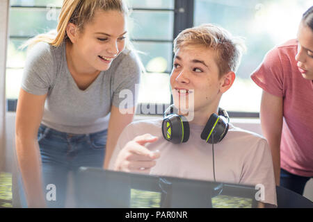 Teenage girls talking to boy using laptop Stock Photo