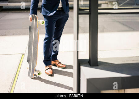 Businessman holding longboard outdoors Stock Photo
