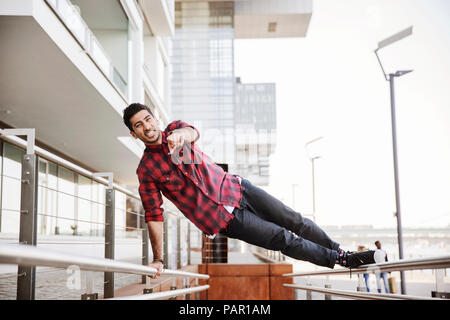 Germany, Cologne, young man exercising on railing at Rheinau harbour Stock Photo