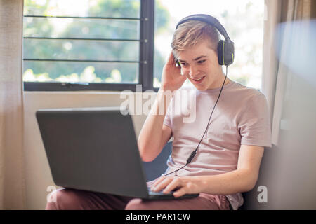 Smiling boy wearing headphones using laptop Stock Photo